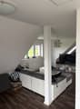White couch, white ottoman, lamps, tv, wooden floor, window, wooden shelves, boxes