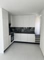 modern kitchen with white cabinets, black marble countertop, white tiled floor, built-in oven, sink, and shelves