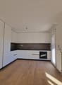 modern kitchen with white cabinets, wooden floor, black countertops, stainless steel sink, built-in oven, sliding glass door