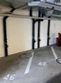 Underground parking garage with floor numbered parking spaces and pipes along the walls.