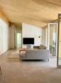 modern living room with wooden table, gray sofa, flatscreen TV, beige rug, wooden ceiling