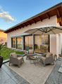Outdoor seating area with 4 chairs, table, umbrella, rug, plants, and lanterns