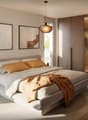 Modern styled bedroom with wooden floor, a large double bed with white bedding, two paintings on the wall, nightstand with a lamp and a small plant, and a built-in wardrobe with glass doors.