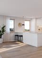 Dining room with a table and chairs, kitchen island, white cabinets, modern pendant lights, large windows, plants, wooden floor