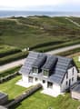 Modern house with solar panels, surrounded by green landscape, sea view