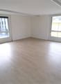 empty room, wooden floor, white walls, large windows, kitchen area with sink and stove