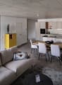 Open plan living and dining area with modern furniture, large windows, and a yellow storage unit.