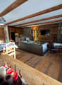 living room with wooden floor, wooden beams, dining table, couch, TV, fireplace, dining chairs, wooden cabinet, lamps, picture frames