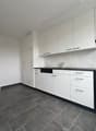 modern kitchen with white cabinets, black countertops, integrated dishwasher, washing machine, oven, sink, faucet