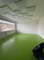 Empty room with green floor, white walls, large window, and ceiling panels