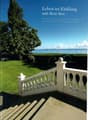 white wooden railing, green lawn, large tree, beach and ocean visible