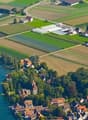 Aerial view of several buildings, houses and farmlands by a river