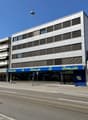 white multi-story building, blue storefront, street sign, entrance to store, fire hydrant, parked car