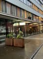 modern office building with glass walls, metal roof, patio with table and chairs, outdoor plants