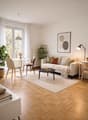white walls, wooden floor, white couch, coffee table, dining table, chairs, radiator, plants, picture frame, lamp, balcony, view