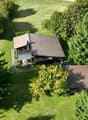 detached house with brown roof, large yard, surrounded by trees, patio