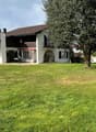 2 story house, brown roof, white walls, large windows, balcony, garden, tree