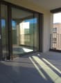 Balcony with sliding glass doors, tiled floor, metal railing, view of another building and trees