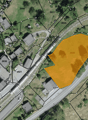 Aerial view of a large, undeveloped land plot with a road running through it. The plot is highlighted in yellow, indicating it is a potential real estate development site.