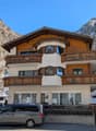 Three story building, wooden balconies, white walls, gray trim, glass windows, snow-covered mountain in the background
