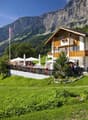Traditional Swiss chalet with restaurant, balcony with tables, flag, surrounded by grass and mountains