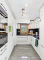 Spacious modern kitchen with white cabinets, black countertops, stainless steel appliances including a dishwasher, and large windows providing a scenic view.