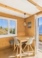 Wooden table, 2 chairs, windows, balcony, wooden floor, open door, lamp