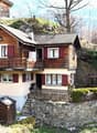 2 story wooden house, red shutters, balcony, stone wall, stairs, chimney