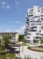 White multistory residential building with balconies and raised ground floor