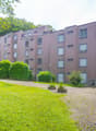 4 story building, multiple windows, green lawn, hedges, paved walkway