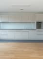 modern kitchen with white cabinets, wooden floor, large window, stainless steel oven, sink with faucet