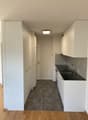 Modern kitchen with high-gloss white cabinets, a black granite countertop, a stainless steel sink, and a chrome faucet. Equipped with built-in appliances, ample storage space, and a sleek design. The kitchen is spacious and well-lit, with a ceiling lamp a