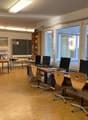 room with several wooden desks, chairs, monitors, shelves, and blackboard