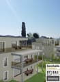 multi-story building, large balconies, green lawn, garden area, various outdoor dining areas