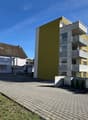 Modern apartment building with yellow facade, brick apartment building, brick sidewalk, brick paving
