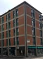 Commercial building, 5 stories, brick wall, green window frames, white air conditioners, awnings, storefronts, street level, 18 units