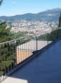 balcony with wood flooring, metal railings, view of a city with mountains in the background