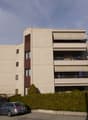 Large multi-story residential building with balconies, beige and brown color scheme