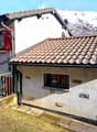 Mountain house, brown roof, white walls, red shutters, small front garden, chimney