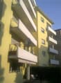 Yellow apartment building, multiple balconies, canopy awning, satellite dish