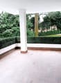 empty balcony with tiled floor and column, plants, trees in the garden