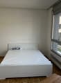empty bedroom with white bed, white wardrobe, parquet floor, large windows