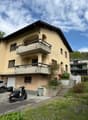 2 story house, beige exterior, garage, balcony, plants, steps, car parked