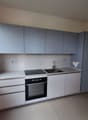 Modern kitchen with white cabinets, gray countertops, a sink, and a gas stove. The kitchen is equipped with a built-in oven and a towel hanging on the wall.
