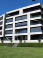 Modern apartment building, white exterior, large windows, balconies, landscaped lawn