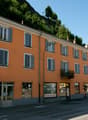Orange facade, 4 floors, multiple balconies, windows, shops on ground floor