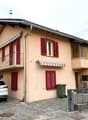 Two-story house, beige exterior, red shutters, balcony, car parked in front
