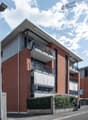modern apartment building, brick facade, multiple balconies, parking sign