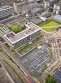 Industrial complex with multiple buildings, parking lot, solar panels, greenery, rooftop garden, wide roads, street lights