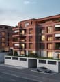Multi-story apartment building with red brick exterior, balconies, and parking spaces in the front.